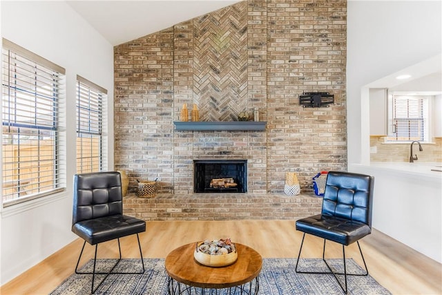 sitting room featuring lofted ceiling, a brick fireplace, and wood finished floors