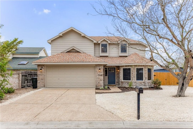 traditional home featuring an attached garage, a shingled roof, fence, and concrete driveway