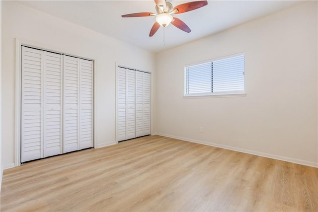 unfurnished bedroom with ceiling fan, two closets, light wood-style flooring, and baseboards