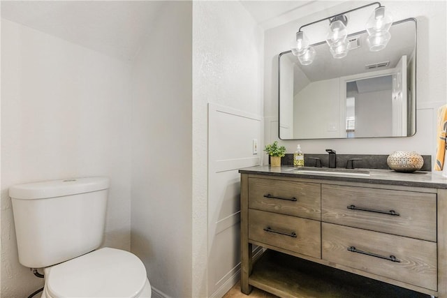 bathroom with lofted ceiling, visible vents, vanity, and toilet