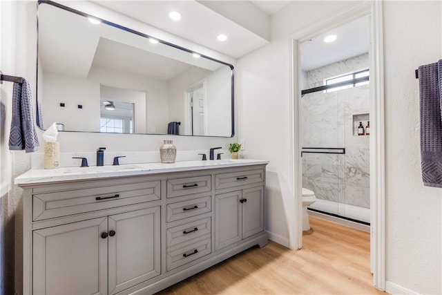 full bath with a wealth of natural light, wood finished floors, a sink, and a marble finish shower