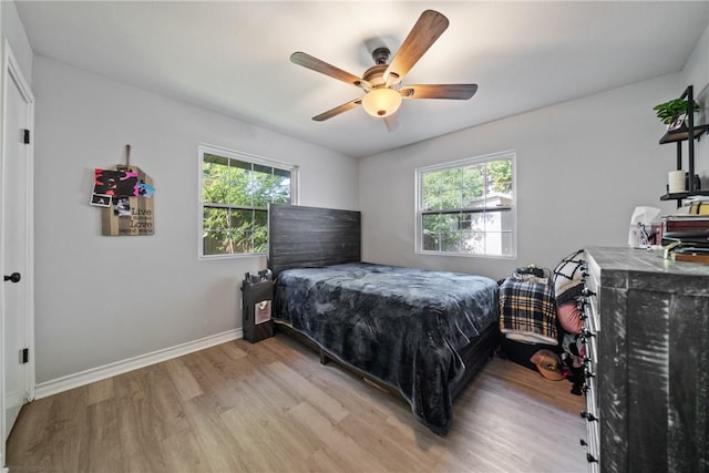 bedroom featuring light wood finished floors, baseboards, and a ceiling fan