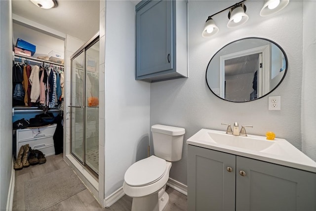 bathroom featuring wood finished floors, a shower stall, and toilet