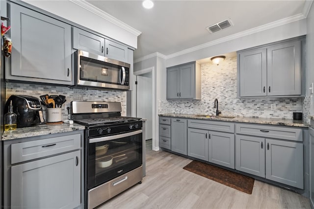 kitchen featuring stainless steel appliances, light hardwood / wood-style floors, light stone countertops, crown molding, and decorative backsplash