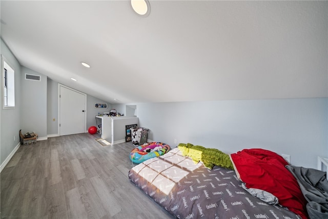 unfurnished bedroom featuring lofted ceiling, wood finished floors, visible vents, and baseboards