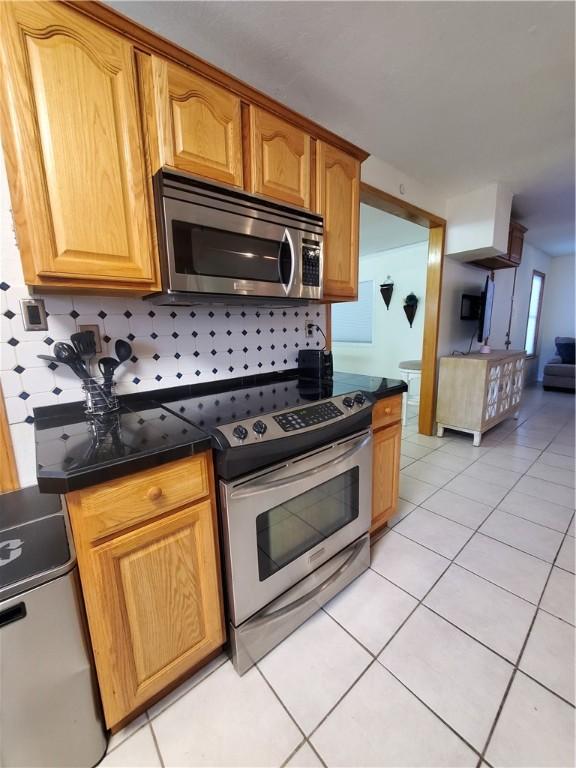 5701 Glen Arbor Dr, Corpus Christi, TX 78412 - kitchen with appliances with stainless steel finishes, dark countertops, backsplash, and light tile patterned floors