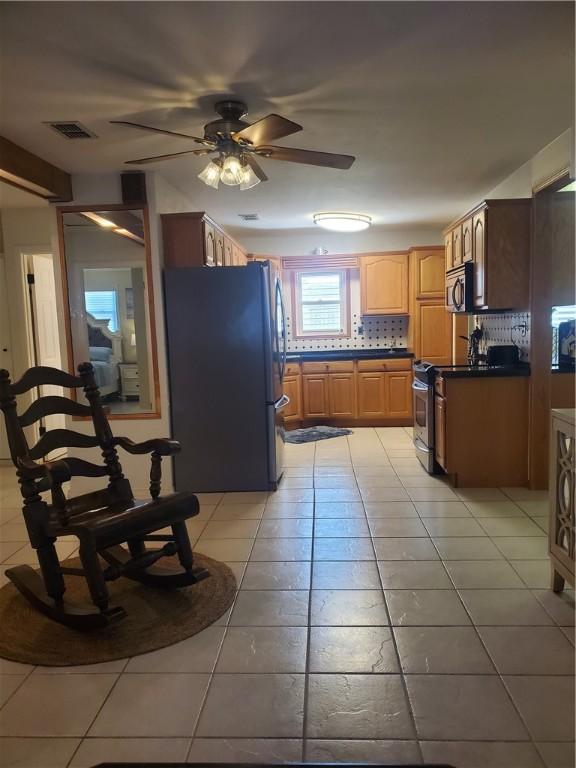 5701 Glen Arbor Dr, Corpus Christi, TX 78412 - kitchen featuring stainless steel appliances, light tile patterned floors, a ceiling fan, dark countertops, and tasteful backsplash