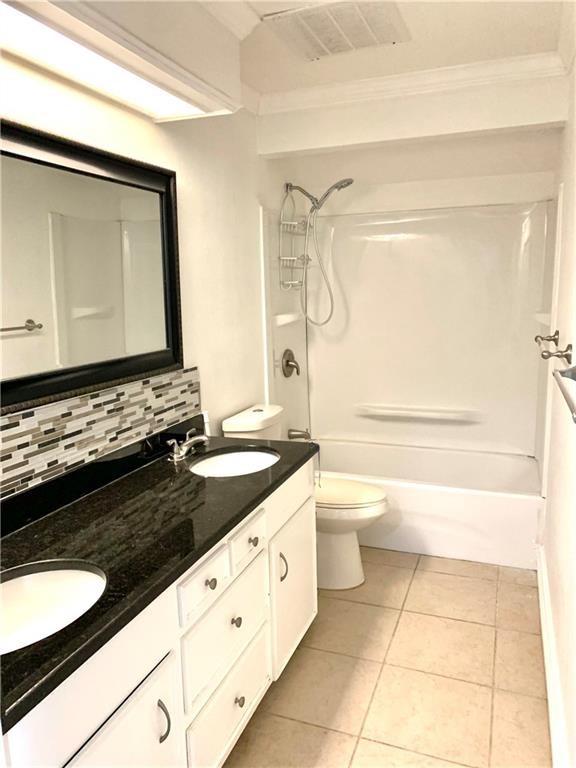 5202 Wentworth Dr, Corpus Christi, TX 78413 - bathroom featuring tasteful backsplash, double vanity, tile patterned flooring, washtub / shower combination, and ornamental molding