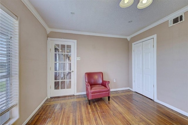 sitting room with a textured ceiling, hardwood / wood-style flooring, and ornamental molding