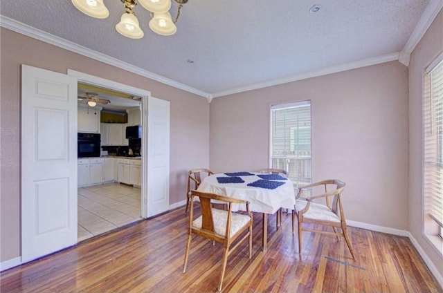 dining space featuring a notable chandelier, light hardwood / wood-style floors, a textured ceiling, and ornamental molding