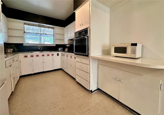 919 W W Ave Unit G, Kingsville, TX 78363 - kitchen with open shelves, white microwave, black oven, white cabinetry, and light tile patterned floors