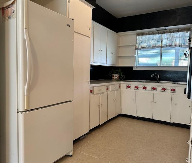 919 W W Ave Unit G, Kingsville, TX 78363 - kitchen featuring freestanding refrigerator, open shelves, white cabinetry, and backsplash