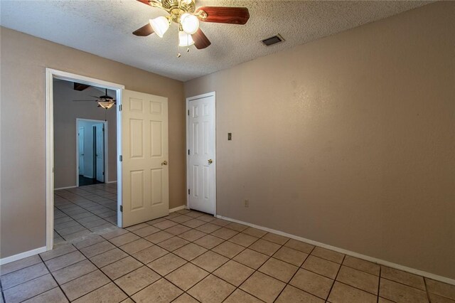 tiled empty room with ceiling fan and a textured ceiling