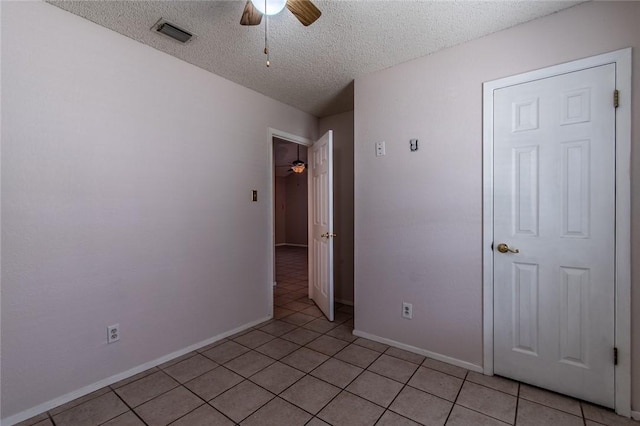 spare room with ceiling fan, light tile patterned floors, and a textured ceiling