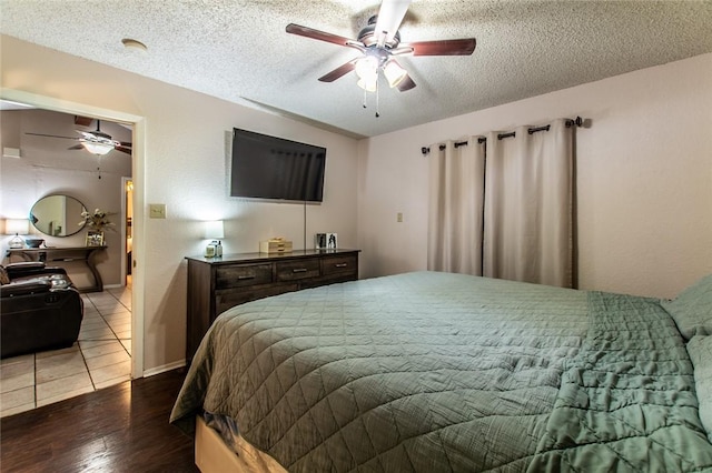 bedroom with ceiling fan, dark hardwood / wood-style flooring, and a textured ceiling