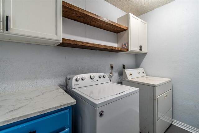 laundry room with washer and dryer, a textured ceiling, and cabinets