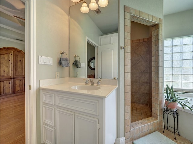 bathroom with hardwood / wood-style flooring, vanity, and a tile shower