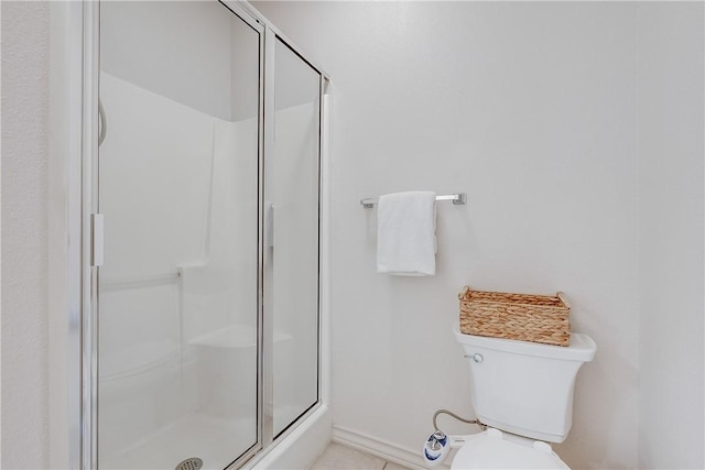 bathroom with baseboards, a stall shower, and toilet