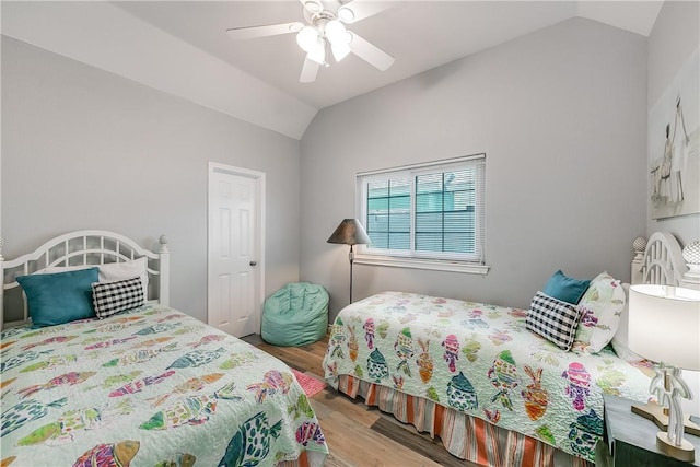 bedroom with ceiling fan, vaulted ceiling, and wood finished floors