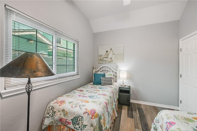 bedroom with baseboards, wood finished floors, and lofted ceiling