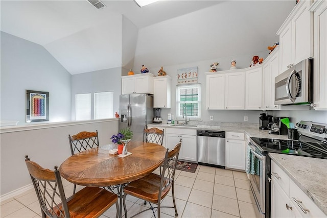 kitchen featuring lofted ceiling, light tile patterned flooring, white cabinetry, a sink, and stainless steel appliances