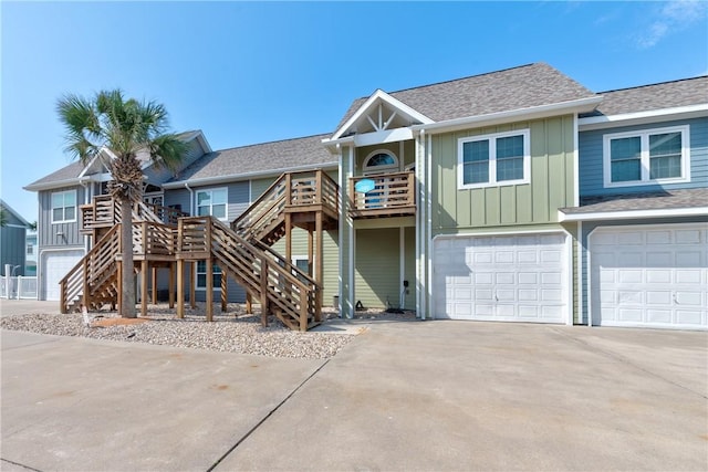 view of front of home featuring stairs, a shingled roof, an attached garage, board and batten siding, and driveway