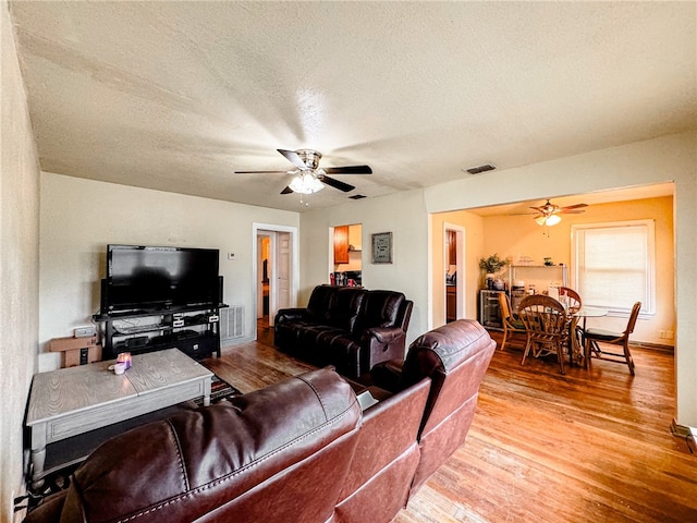 living room with hardwood / wood-style flooring, a textured ceiling, and ceiling fan