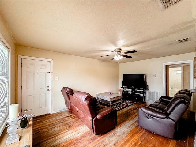 living room featuring a textured ceiling, ceiling fan, and hardwood / wood-style floors