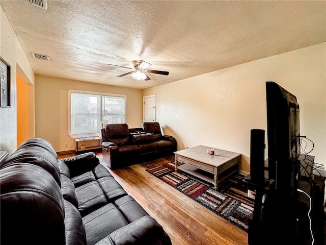 living room featuring a textured ceiling, ceiling fan, and hardwood / wood-style flooring