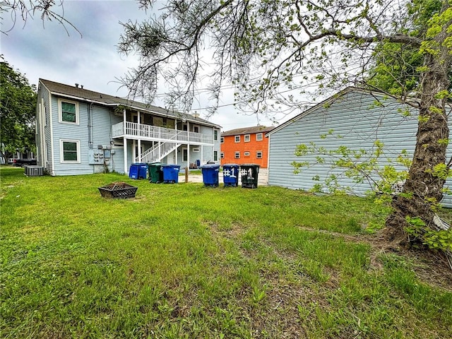 rear view of property featuring a deck, a lawn, and a fire pit