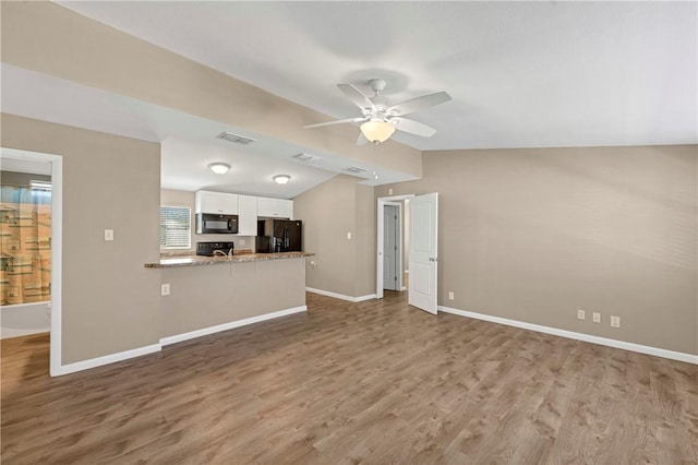 unfurnished living room with hardwood / wood-style floors, vaulted ceiling, and ceiling fan