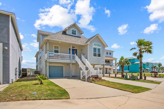 beach home featuring covered porch, central air condition unit, a front lawn, and a garage