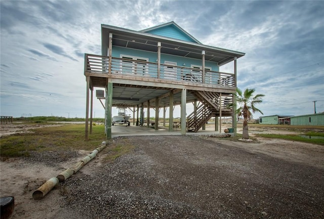 exterior space featuring dirt driveway, a carport, a porch, and stairway