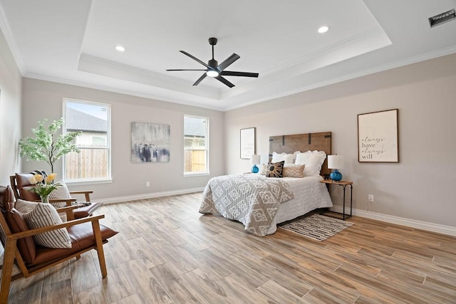 bedroom with light wood-style floors, a raised ceiling, visible vents, and multiple windows