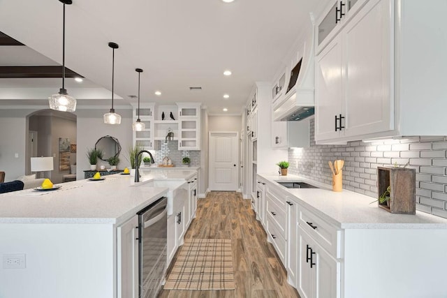 kitchen featuring a spacious island, white cabinetry, hanging light fixtures, dishwasher, and glass insert cabinets