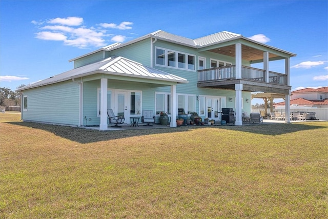 rear view of house with a standing seam roof, french doors, a lawn, and a patio area