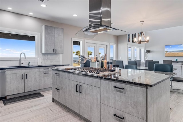 kitchen with a center island, backsplash, appliances with stainless steel finishes, a sink, and extractor fan