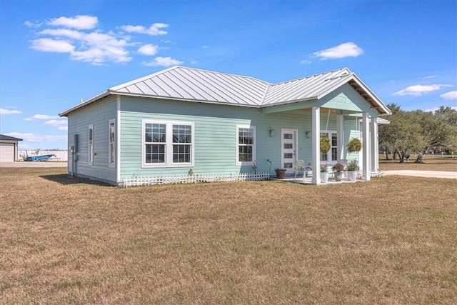 back of property featuring a standing seam roof, a lawn, and metal roof