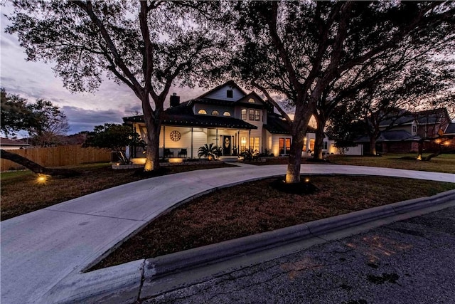 view of front of property with a yard, concrete driveway, fence, and a chimney