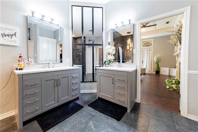 full bathroom featuring visible vents, two vanities, a sink, and a textured wall