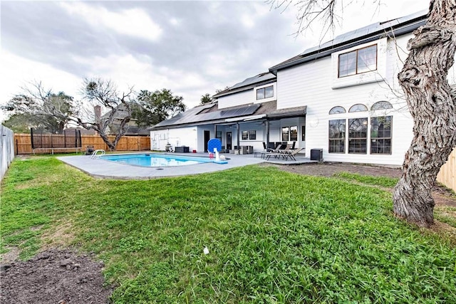 rear view of house featuring a patio, a fenced backyard, solar panels, a yard, and a fenced in pool