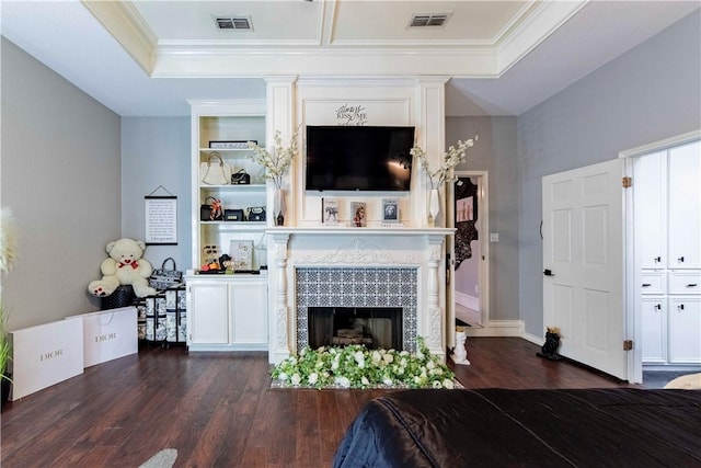 living area featuring built in shelves, dark wood-style flooring, visible vents, and a tiled fireplace