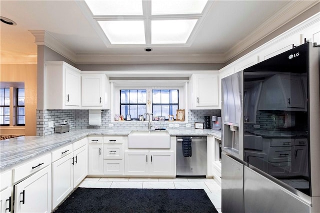 kitchen with light stone countertops, fridge with ice dispenser, stainless steel dishwasher, white cabinetry, and a sink