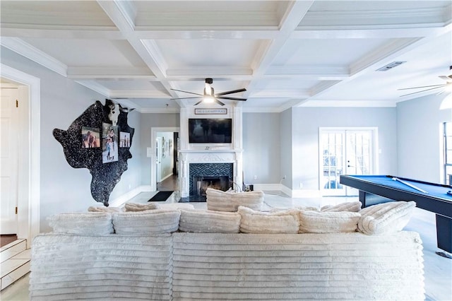 living area featuring beam ceiling, visible vents, a premium fireplace, ceiling fan, and coffered ceiling