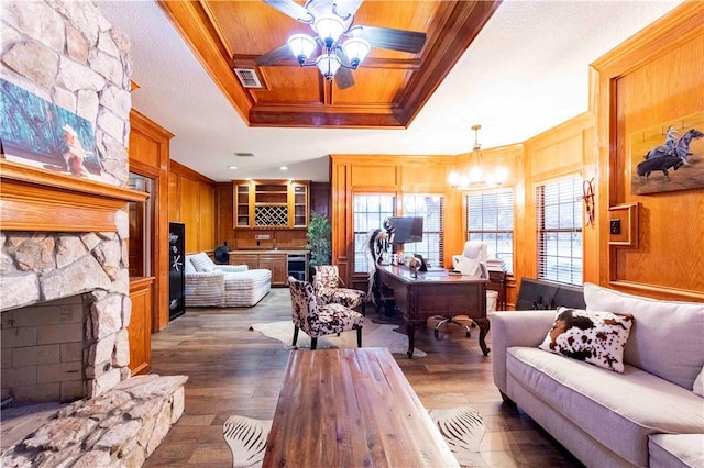 living area featuring a fireplace, wood finished floors, visible vents, a raised ceiling, and crown molding