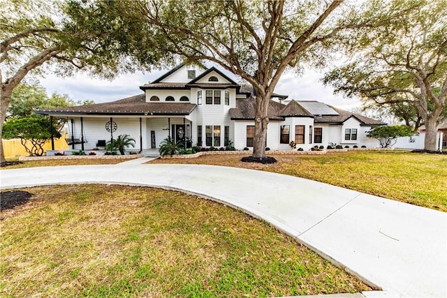 view of front of home with roof mounted solar panels, driveway, and a front lawn