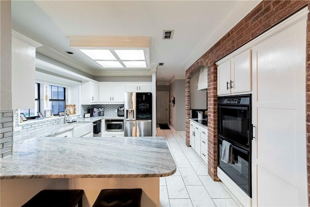 kitchen featuring marble finish floor, crown molding, visible vents, appliances with stainless steel finishes, and a peninsula