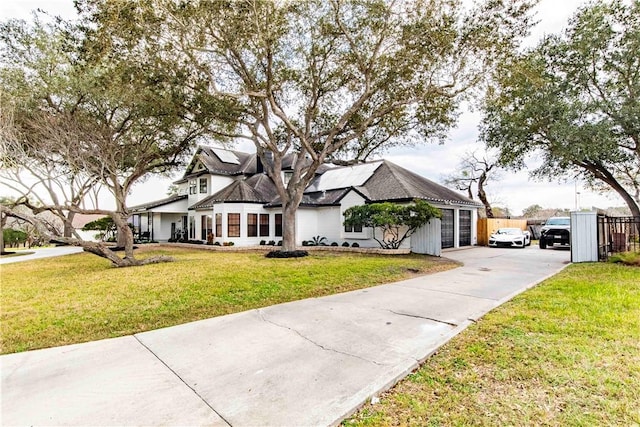 view of front facade featuring a garage, a front lawn, and fence