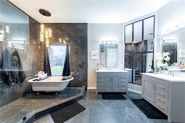 full bathroom featuring marble finish floor, two vanities, a soaking tub, and a sink