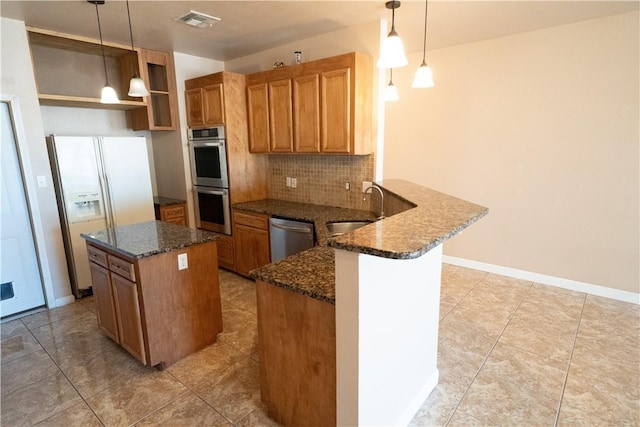 2033 Briarwood Dr, Corpus Christi, TX 78412 - kitchen featuring appliances with stainless steel finishes, a peninsula, backsplash, and brown cabinetry